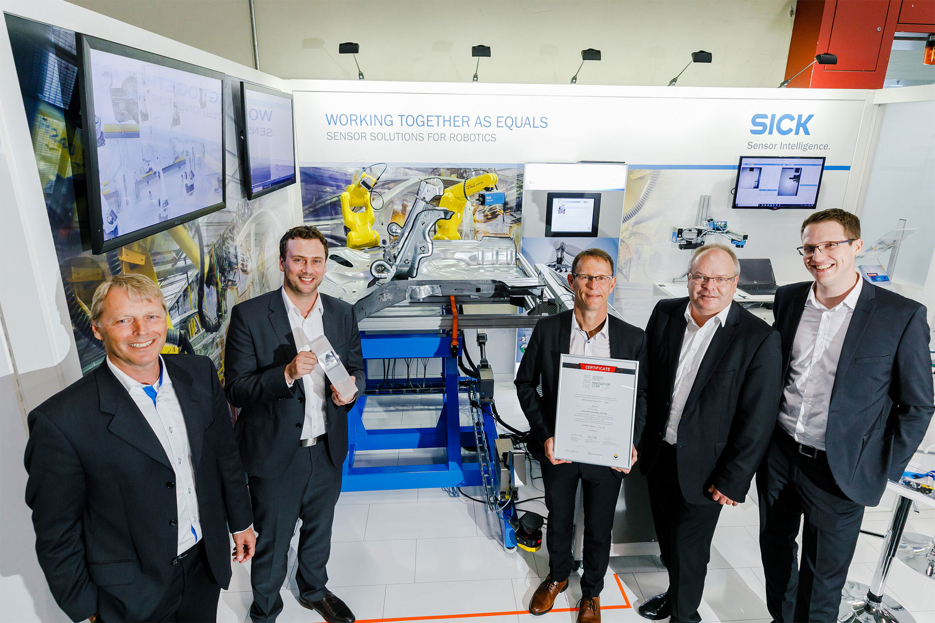 Vertreter der Firma SICK AG freuen sich an ihrem Messestand über die Auszeichnung AEE Innovation Award 2019