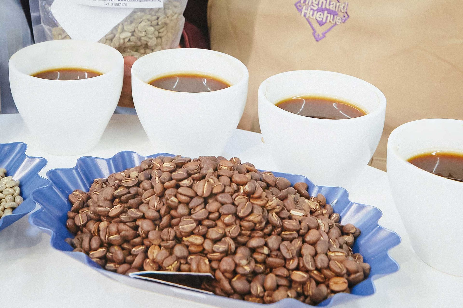 Kaffeebohnen in einer Schale und vier Tassen Kaffee
