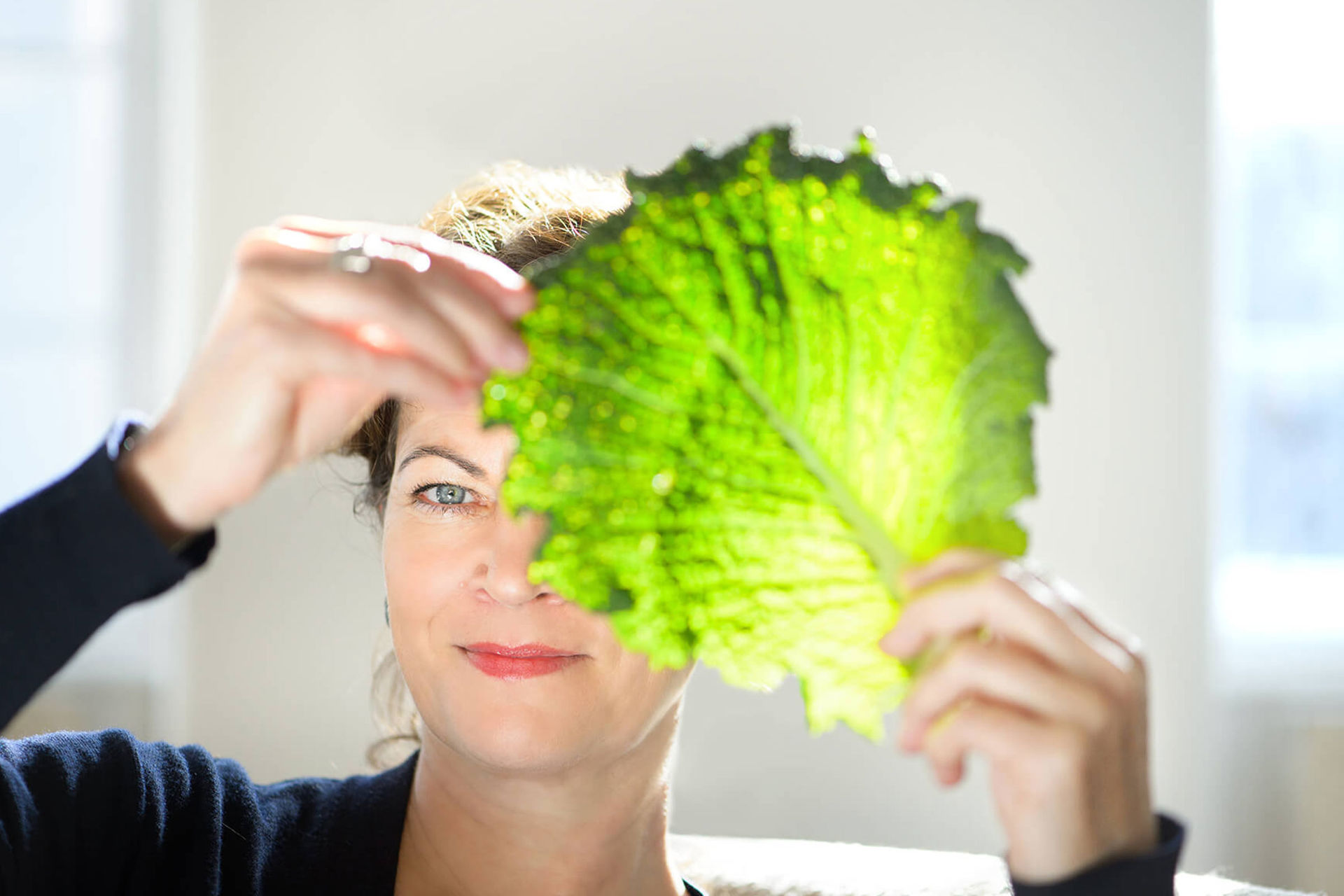 Hanni Rützler schaut durch ein Salatblatt