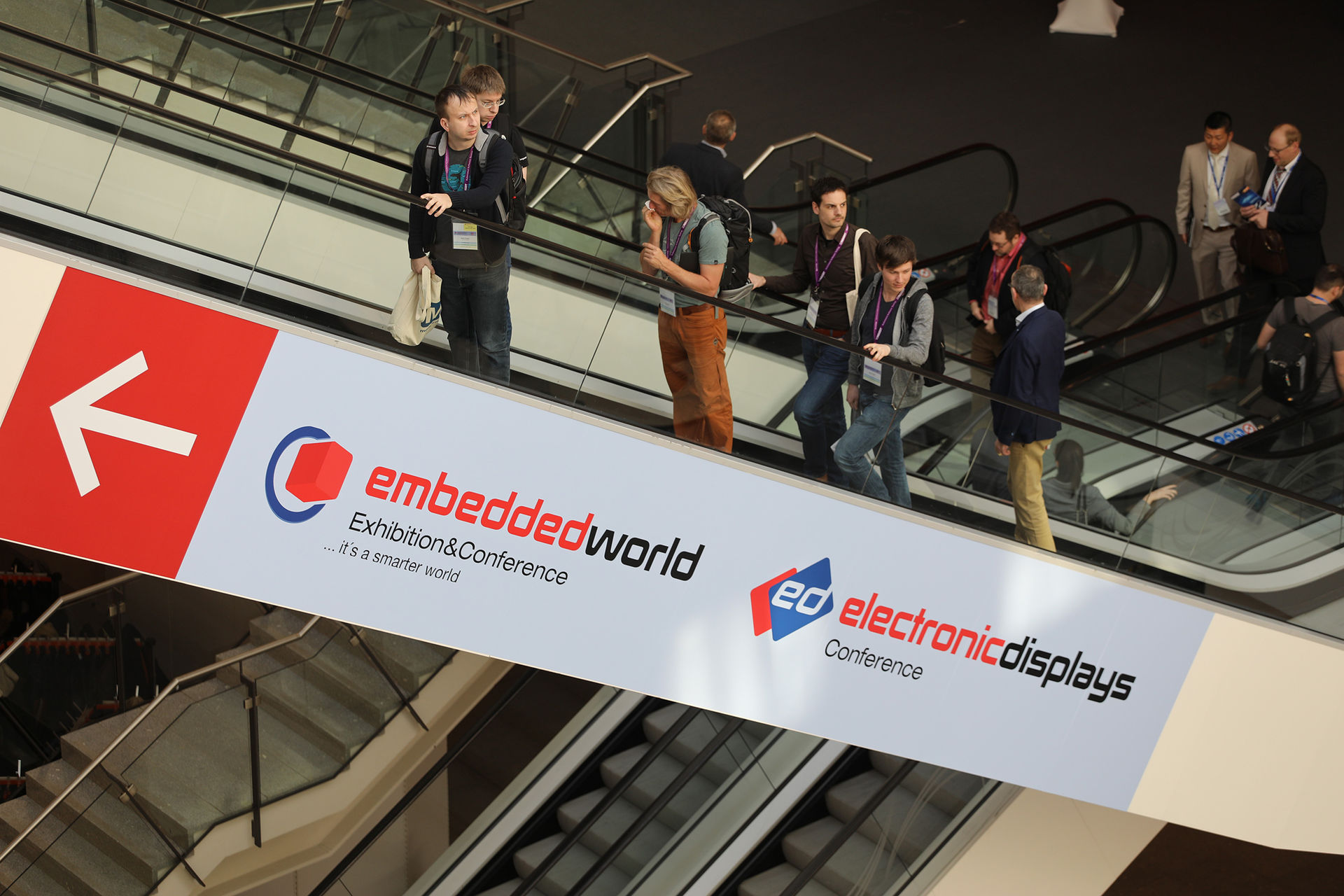 Auf dem Foto sehen Sie Konferenzteilnehmer auf einer Rolltreppe