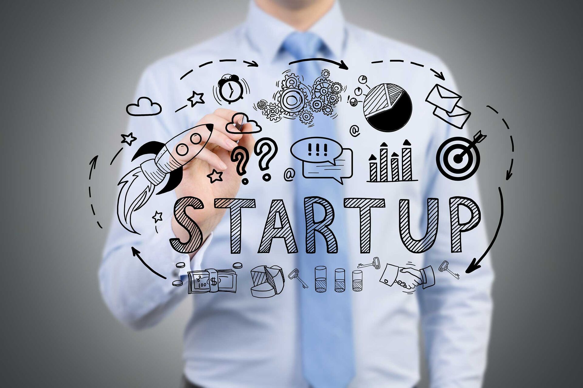 Ein Mann in Geschäftskleidung steht hinter dem Schriftzug Startup. Mit seiner Hand tippt er auf eines von unterschiedlichen Symbolen, die für Startups stehen sollen