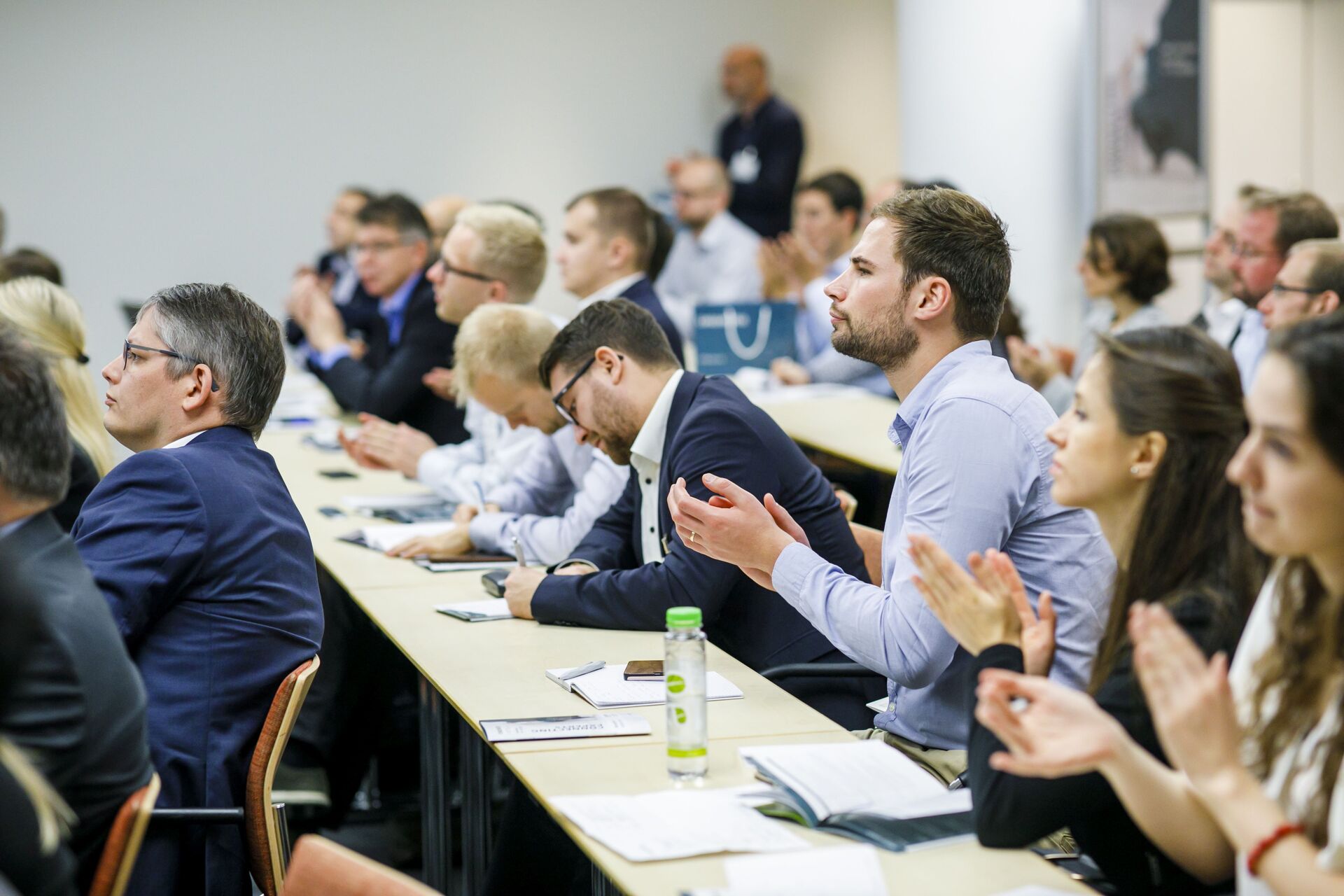 Eine Gruppe von Business Leuten sitzt in einem Konferenzraum und applaudieren.