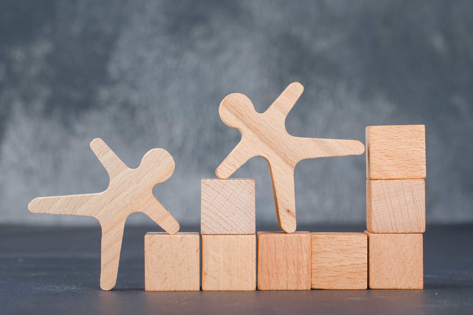 Business-Konzept mit Holzblöcken mit hölzernen menschlichen Figuren auf dunklem Hintergrund.