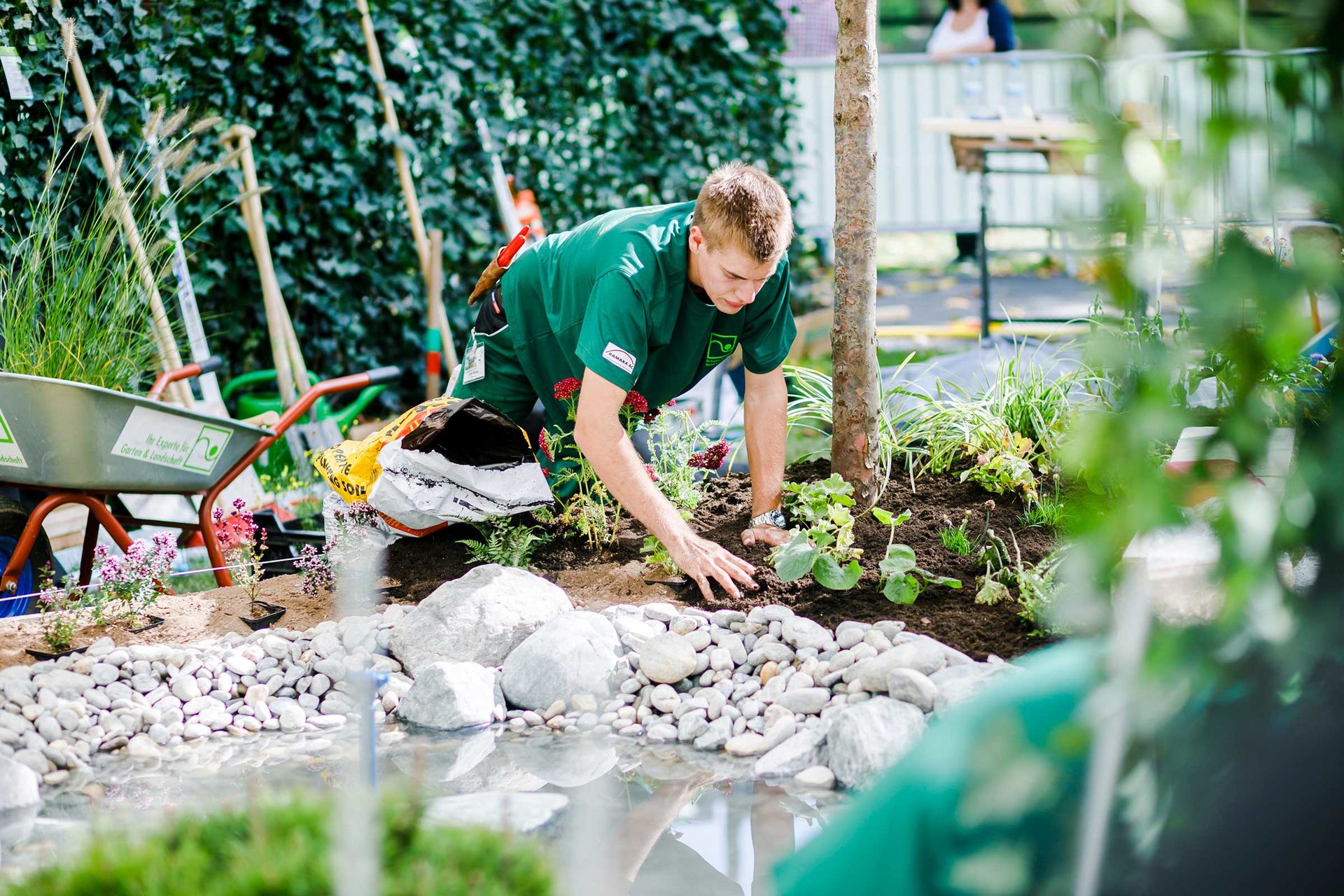 Ein Landschaftsgärtner setzt Grünpflanzen und Blumen in einem neu angelegten Garten