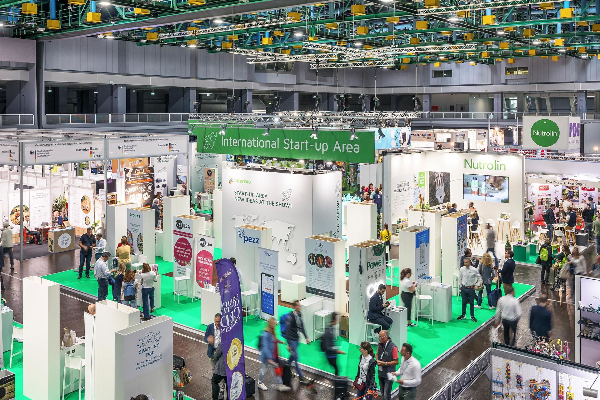 Auf der Interzoo 2022 laufen Besucher interessiert durch die Start-up Halle mit Fresh Ideas Stage, International Start-up Area und gefördertem Gemeinschaftsstand des Bundes und suchen das Gespräch zu innovativen Heimtierprodukten.