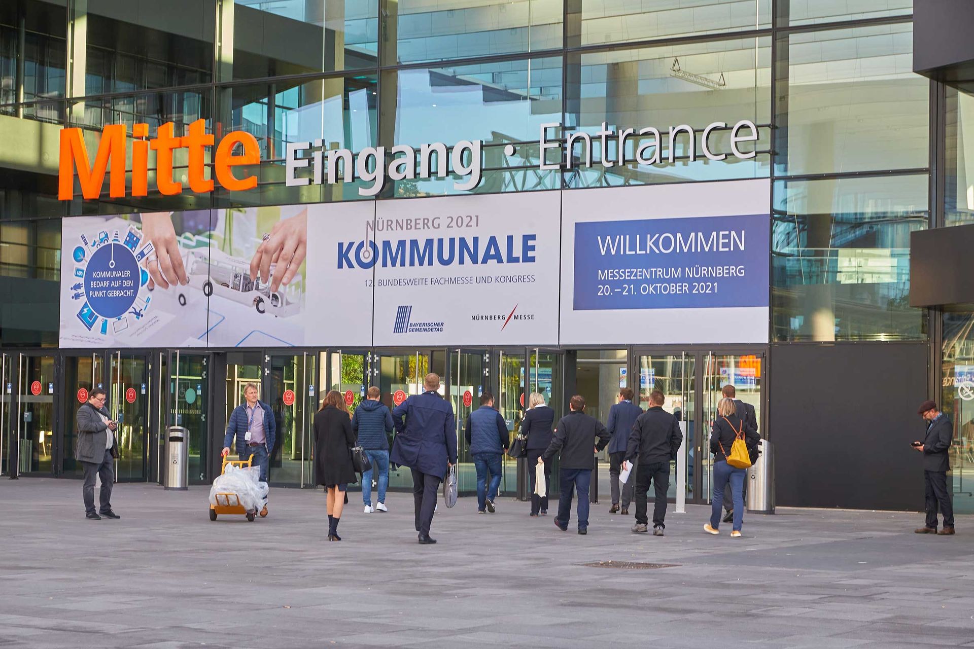 Das Bild zeigt Menschen, die Richtung Messeeingang laufen und die KOMMUNALE 2021 in Nürnberg besuchen