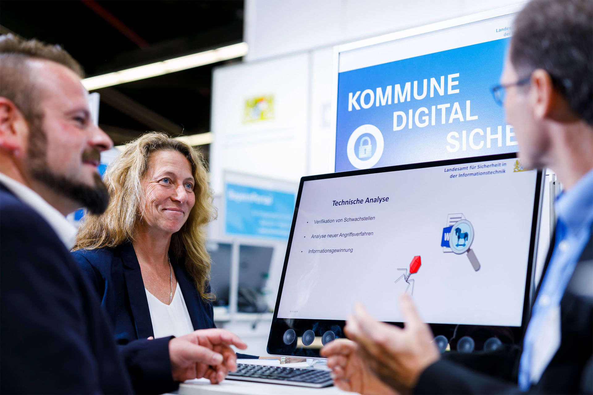 Das Bild zeigt eine Frau und zwei Männer, die in einem Gespräch auf einem Messestand der Kommunale über digitale Kommunen reden.