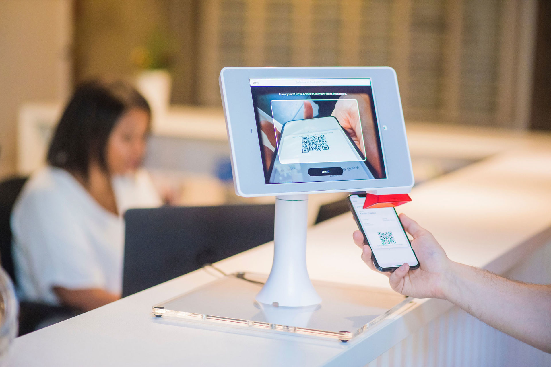 Das Bild zeigt eine physische Zugangskontrolle, in dem ein Handy mit QR-Code an einen Scanner gehalten wird.