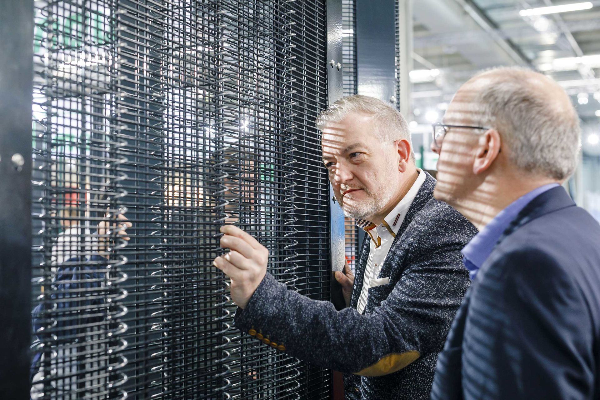 Das Bild zeigt zwei Männer, die einen Zaunschutz begutachten.