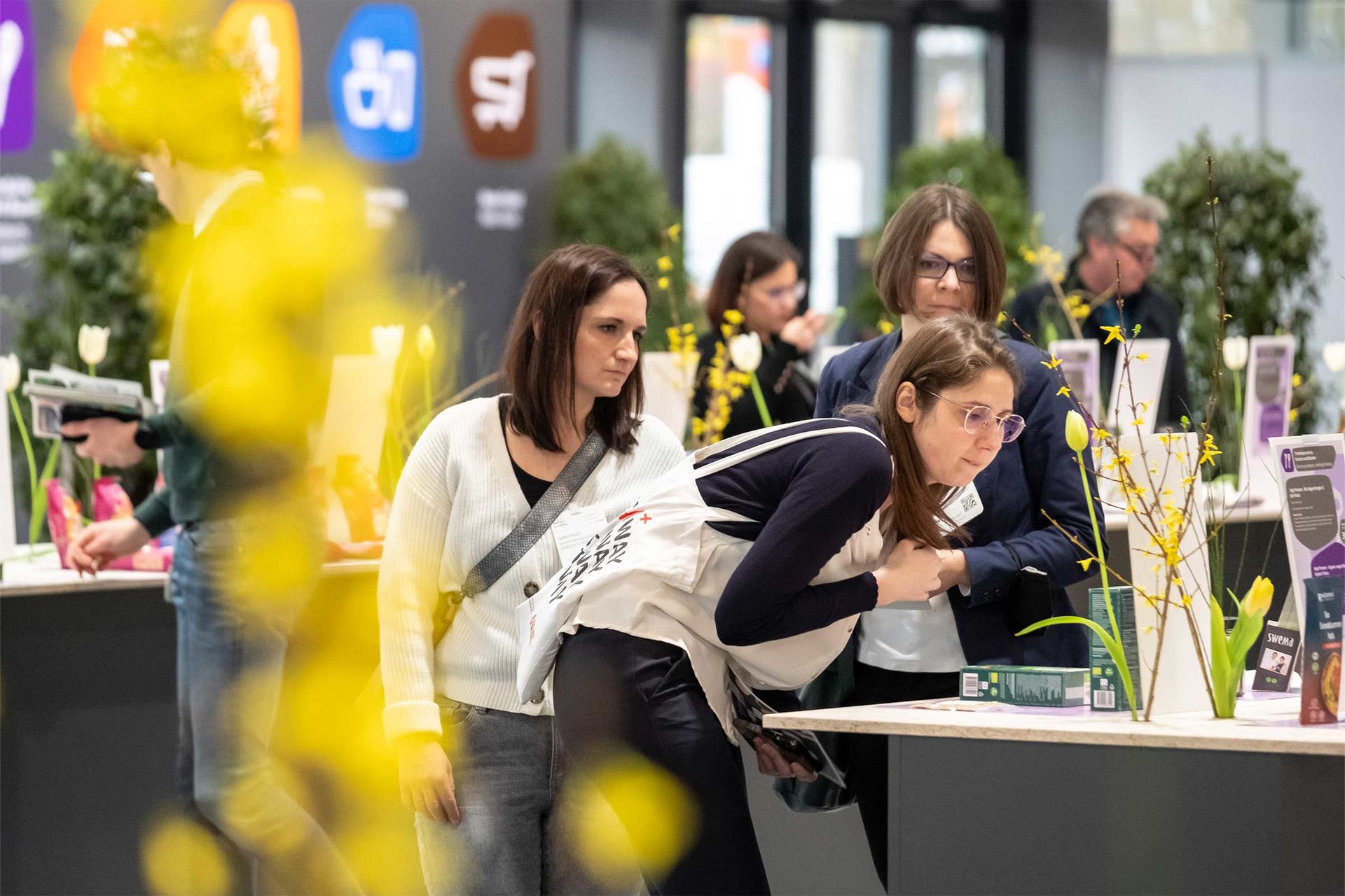 3 Personen betrachten Produkte am Neuheitenstand