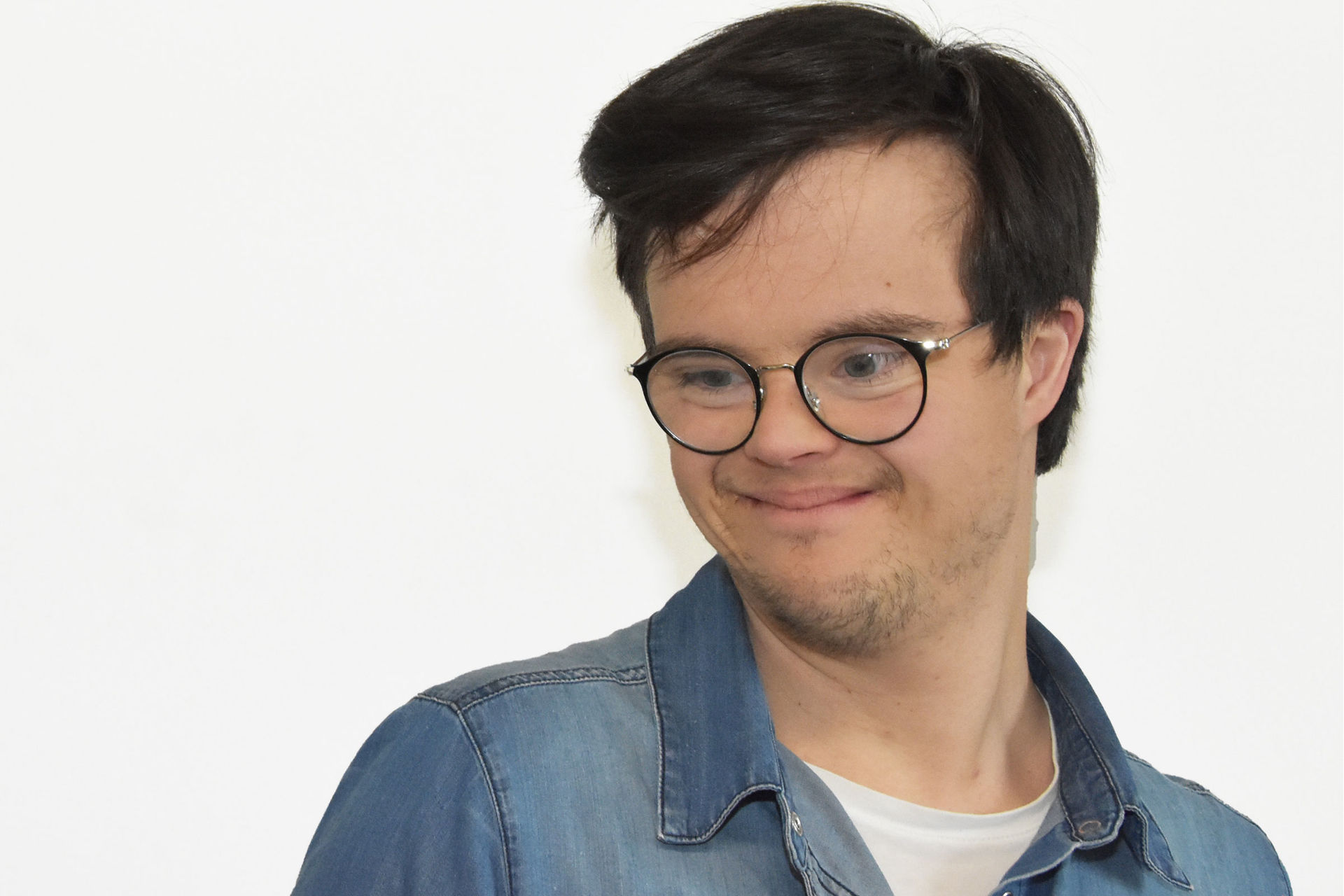Das Bild zeigt Leonhard Ley als Porträt. Er hat schwarze Haare und trägt eine Brille mit schwarzem Rahmen. Er schaut nach unten und lächelt.